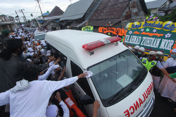 Warga menyambut iring-iringan mobil jenazah KH Ahmad Zuhdiannoor saat melintas di jalan menuju rumah duka di Banjarmasin, Kalimantan Selatan, Sabtu, 2 Mei 2020.