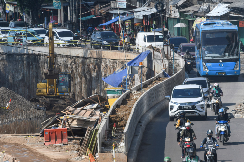 Sejumlah pengendara kendaraan melintas di samping proyek pembangunan Underpass Senen Extension di kawasan Senen, Jakarta.