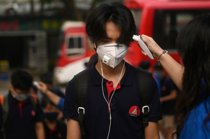 Di sebuah sekolah di Hanoi bagian barat, para siswa kelas 6-9 berbaris dengan tenang saat satu per satu diperiksa suhu tubuhnya sebelum masuk ke ruang kelas. Anak-anak ini mulai sekolah lagi setelah tiga bulan berada di rumah.