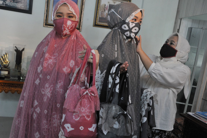 Desainer asal Sumatera Selatan Tria Gunawan merapikan masker yang dikenakan model di Rumah Busana Tria Palembang,Sumsel, Kamis, 7 Mei 2020. 