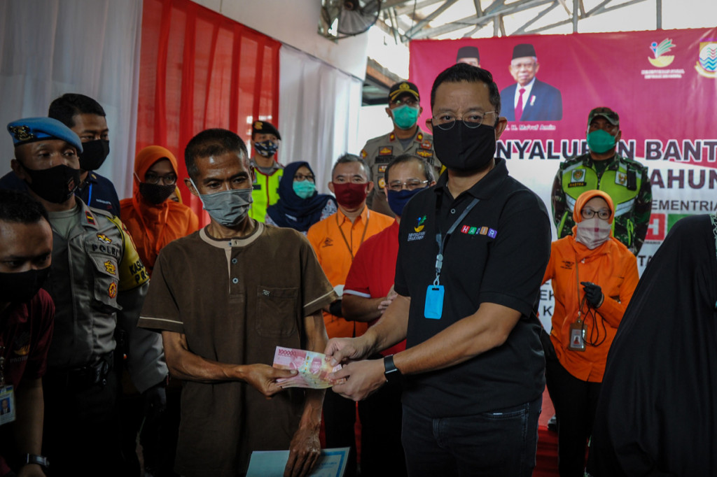 Menteri Sosial Juliari P Batubara (kedua kanan) memberikan Bantuan Sosial Tunai (BST) kepada Keluarga Penerima Manfaat (KPM) saat melakukan kunjungan kerja di Cimahi, Jawa Barat. 