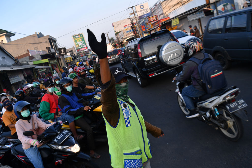Warga membantu mengatur lalu lintas kendaraan yang padat di Jalan Raya Sawangan, Depok, Jawa Barat.
