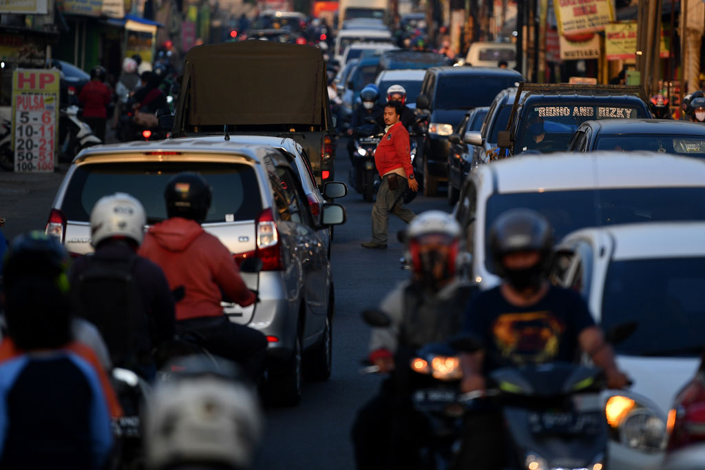 Seorang warga menyeberang jalan di tengah keramaian lalu lintas di Jalan Raya Sawangan, Depok, Jawa Barat.