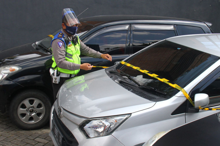 Polisi memasang garis polisi pada mobil travel ilegal yang ditahan di pos pemeriksaan Pembatasan Sosial Berskala besar (PSBB) Balearjosari, Malang, Jawa Timur, Jumat, 22 Mei 2020. 