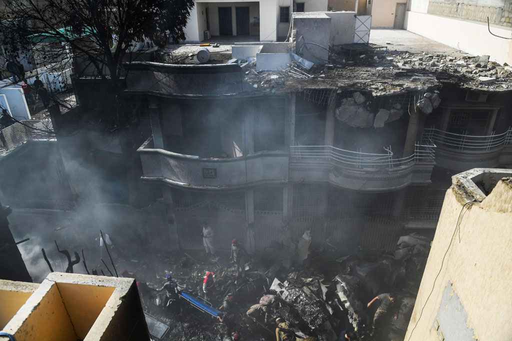 Petugas penyelamat mencari korban di lokasi jatuhnya pesawat Pakistan International Airlines (PIA) di sebuah kawasan perumahan di Karachi, Jumat, 22 Mei 2020.