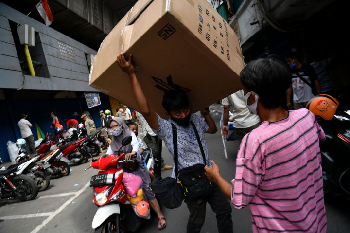 Warga memanggul barang dagangannya saat berlangsung penertiban di kolong jembatan layang Pasar Pagi Asemka, Jakarta Barat.
