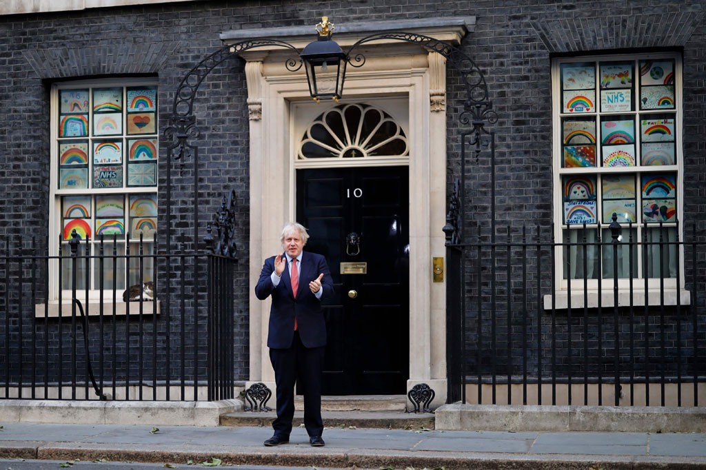 Perdana Menteri Boris Johnson, yang baru saja mengumumkan pelonggaran karantina wilayah terbatas, bertepuk tangan di depan kantornya di Downing Street.