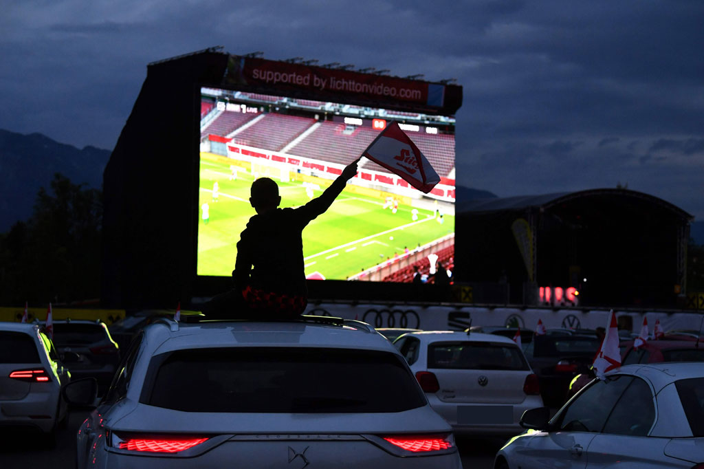 Penggemar sepak bola mengikuti final Piala Austria antara FC Red Bull Salzburg dan SC Austria Lustenau lewat layar raksasa dari mobil mereka di drive-in di Salzburg.