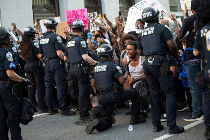 Seorang pria berteriak dengan emosi di depan seorang polisi yang berlutut, sementara ratusan demonstran lainnya memprotes kematian George Floyd di sebelah Gedung Putih, Washington, DC, pada 31 Mei 2020. 