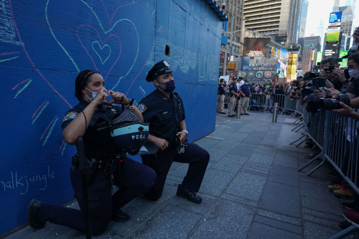 Dua petugas kepolisian Kota New York berlutut saat demonstran berunjuk rasa di Times Square, New York atas kematian George Floyd oleh seorang petugas kepolisian Minneapolis, pada 31 Mei 2020.
