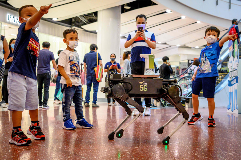Seekor robot anjing yang bernama K9 membagikan hand sanitizer kepada anak-anak dan pengunjung di sebuah pusat perbelanjaan di Bangkok, Thailand, Kamis, 4 Juni 2020.