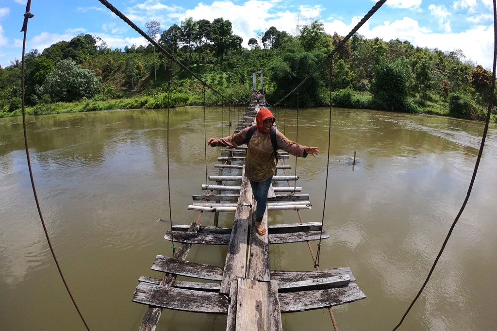 Warga menyeberangi jembatan yang rusak di Desa Tarutung, Batang Merangin, Kerinci, Jambi, Kamis, 4 Juni 2020.