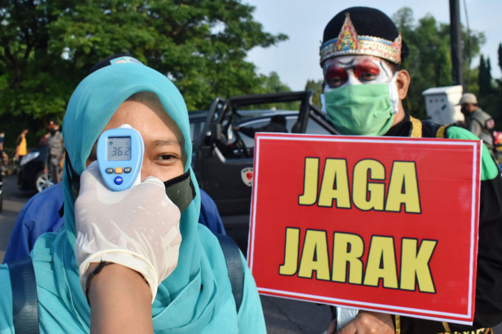 Petugas memeriksa suhu tubuh pengunjung di jalan masuk kawasan hari bebas kendaraan bermotor atau car free day Taman Lalu Lintas Bantaran Sungai Madiun di Kota Madiun, Jawa Timur, Minggu.
