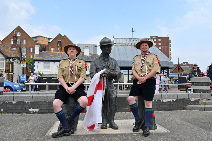 Dua warga lokal berpakaian pramuka berfoto bersama patung pendiri Kepanduan, Robert Baden-Powell di dermaga di Bournemouth, Inggris, Kamis, 11 Juni 2020 waktu setempat.
