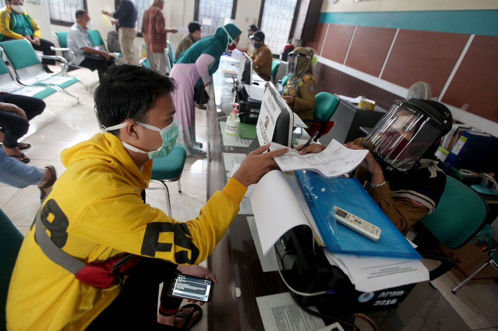 Petugas loket mengenakan pelindung wajah saat memeriksa berkas-berkas masyarakat saat proses perekaman KTP Elektronik di Kecamatan Pamulang, Tangerang Selatan, Banten.