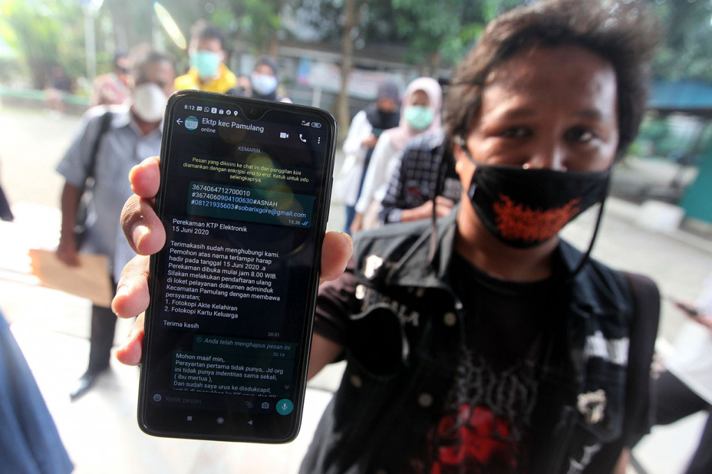 Masyarakat menunjukkan pesan balasan untuk bisa masuk antrian perekaman KTP Elektronik di Kecamatan Pamulang, Tangerang Selatan, Banten.