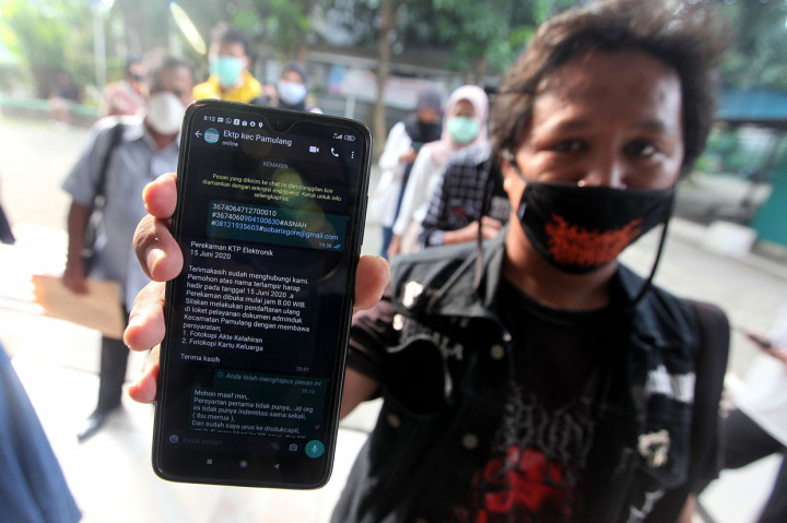 Masyarakat menunjukkan pesan balasan untuk bisa masuk antrian perekaman KTP Elektronik di Kecamatan Pamulang, Tangerang Selatan, Banten.