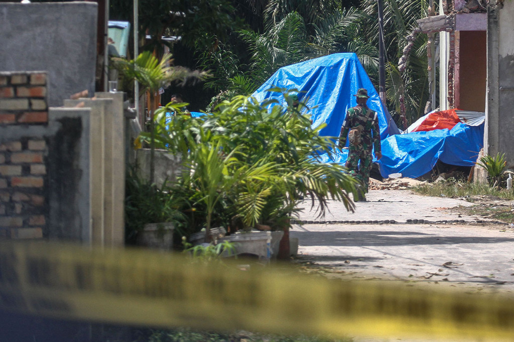 Personel TNI AU Lanud Roesmin Nurjadin Pekanbaru menutup pesawat tempur yang menimpa rumah warga dengan terpal di Desa Kubang Jaya, Kabupaten Kampar.