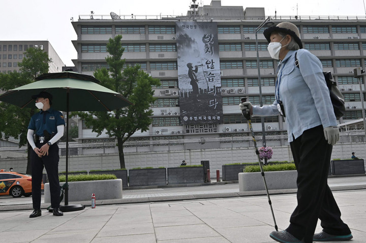 Seorang polisi (kiri) berjaga-jaga di depan Gedung Kedutaan Besar Amerika Serikat di Korea Selatan yang memajang spanduk untuk memperingati 70 tahun Perang Korea, di Seoul pada 16 Juni 2020.