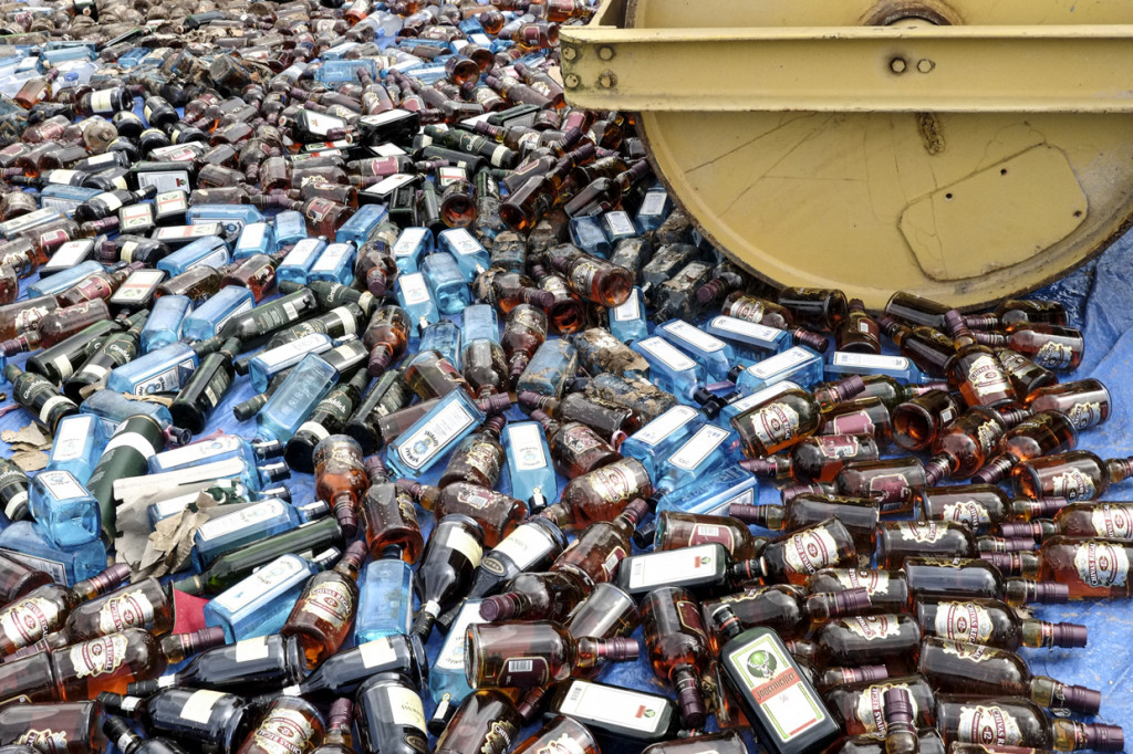 Petugas mengoperasikan alat berat untuk memusnahkan barang bukti minuman keras ilegal di Dermaga Ditpolairud Polda Kepulauan Bangka Belitung, Air Anyir, Kabupaten Bangka, Kepulauan Bangka Belitung.