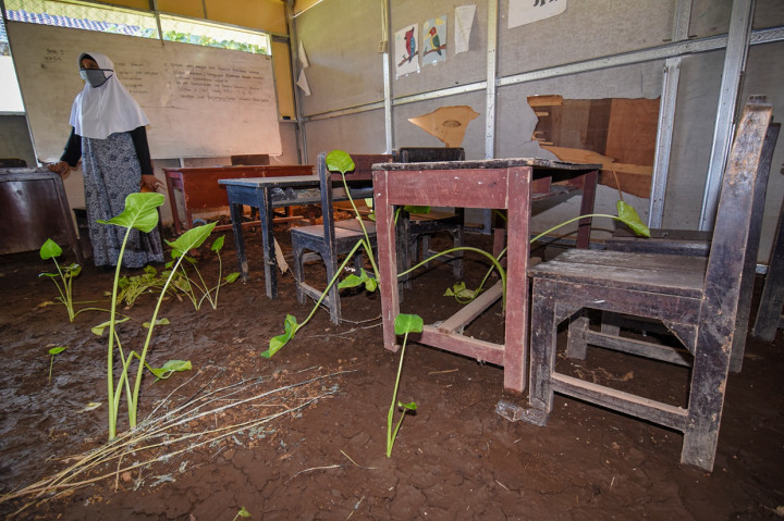 Seorang guru mengecek kondisi ruang kelas SMPN 2 Gunungsari, Desa Mekarsari, Kecamatan Gunungsari, Lombok Barat, NTB, yang rusak dan ditumbuhi tanaman talas, Kamis, 18 Juni 2020.