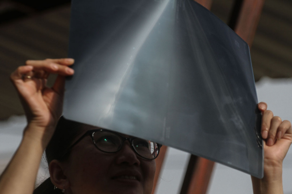 Seorang warga menggunakan hasil foto rontgen untuk mengamati proses terjadinya Gerhana Matahari Sebagian yang terlihat di Pekanbaru, Riau. ANTARA Foto/Rony Muharrman