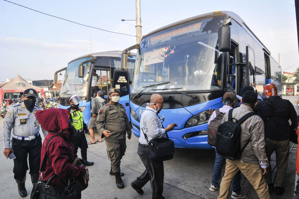 Petugas Dinas Perhubungan dan Satpol PP mengatur jarak penumpang sebelum menaiki bus bantuan pemprov DKI Jakarta di Stasiun Tambun, Kabupaten Bekasi, Jawa Barat.