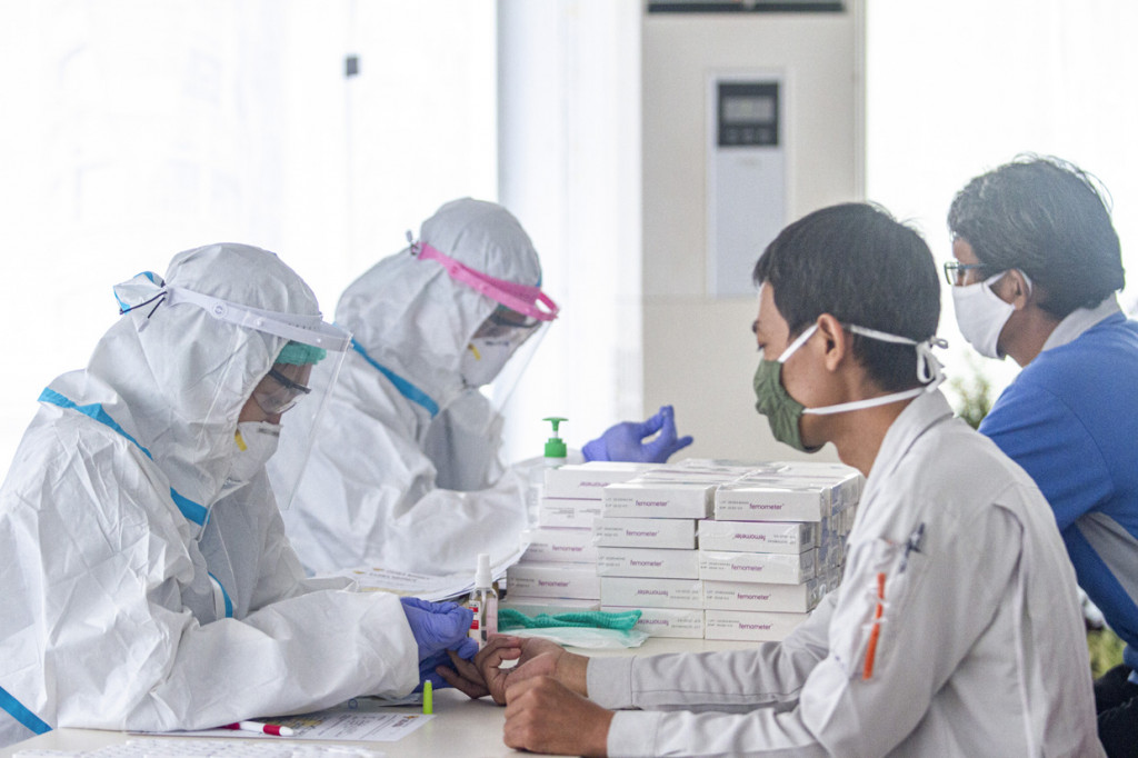 Petugas medis mengambil sample darah buruh saat tes diagnostik cepat Covid-19 di kawasan Suryacipta, Karawang, Jawa Barat.