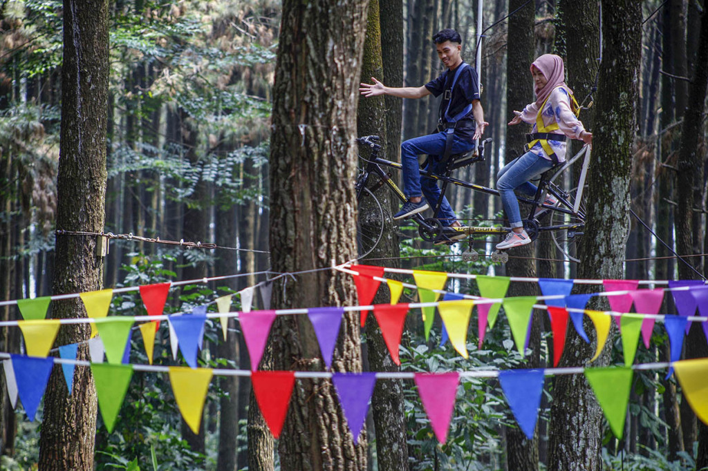 Wisatawan menaiki sepeda ganrung saat berwisata di Gunung Pancar, Kabupaten Bogor, Jawa Barat.