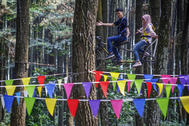 Wisatawan menaiki sepeda ganrung saat berwisata di Gunung Pancar, Kabupaten Bogor, Jawa Barat.