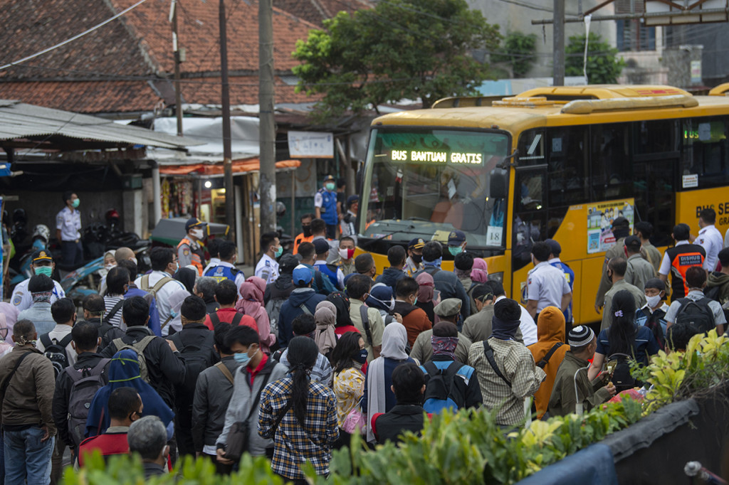 Sejumlah warga mengantre masuk ke dalam bus yang disediakan pemerintah untuk antisipasi membludaknya calon pemnumpang Kereta Rel Listrik (KRL) Commuterline di Stasiun KA Kota Bogor, Jawa Barat.