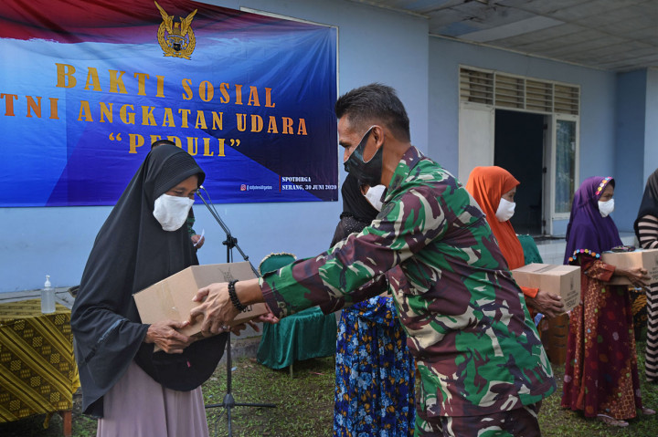 Paban V Asisten Potensi Dirgantara (Aspotdirga) TNI Angkatan Udara Kol. Tek Agus Syamlin (kanan) menyerahkan bantuan paket sembako kepada warga saat acara Bakti Sosial di Pangkalan Detasemen TNI AU Gorda, Serang.