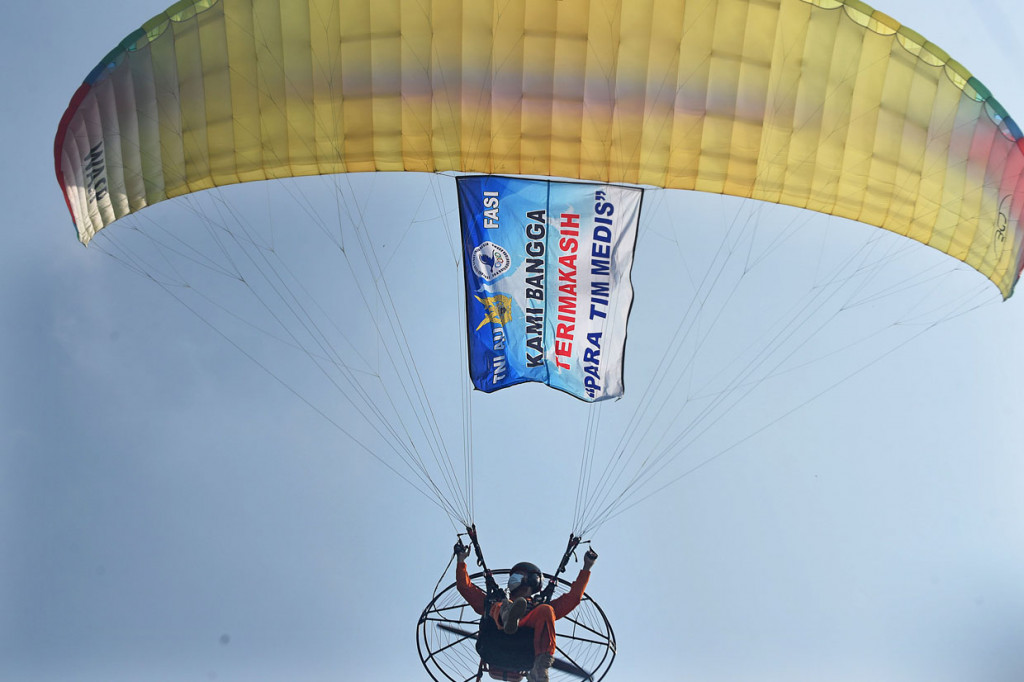 Anggota Federasi Aero Sport Indonesia (FASI) membentangkan banner uncapan terima kasih untuk tenaga medis dengan paralayang saat acara Bakti Sosial Spotdirga (Staf Potensi Dirgantara) TNI AU di Pangkalan Detasemen TNI AU Gorda, Serang, Banten.
