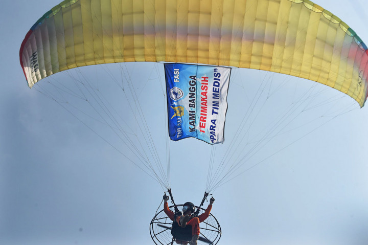 Anggota Federasi Aero Sport Indonesia (FASI) membentangkan banner uncapan terima kasih untuk tenaga medis dengan paralayang saat acara Bakti Sosial Spotdirga (Staf Potensi Dirgantara) TNI AU di Pangkalan Detasemen TNI AU Gorda, Serang, Banten.
