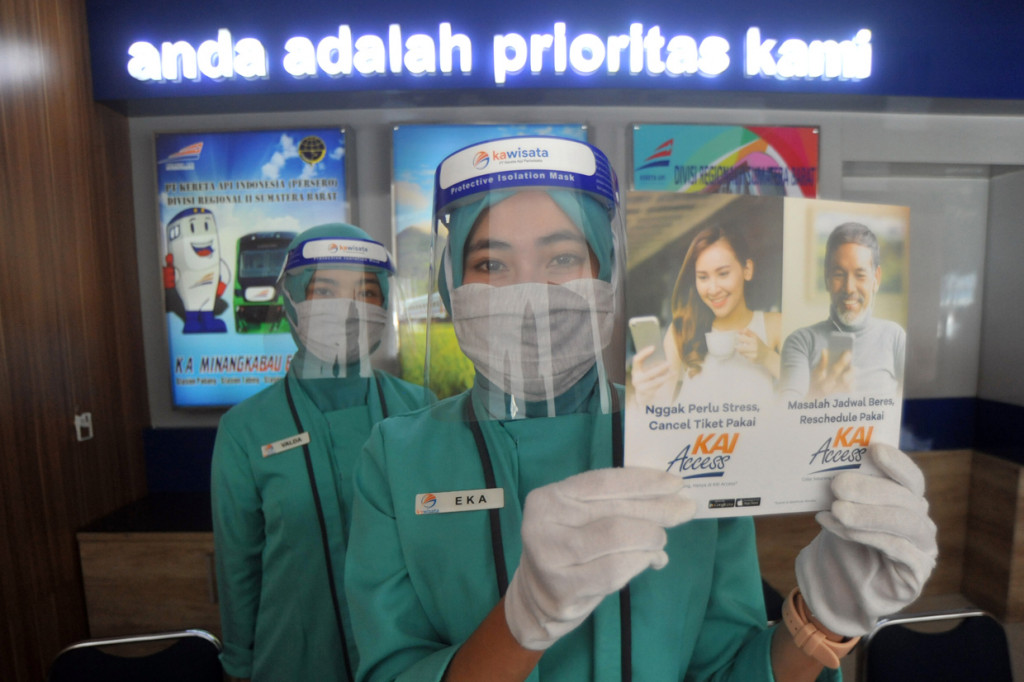 Petugas loket menggunakan APD menunjukan brosur untuk memesan dan refund tiket kereta api di Stasiun Simpang Haru, Padang, Sumatera Barat, Rabu 1 Juli 2020.