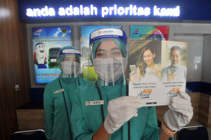Petugas loket menggunakan APD menunjukan brosur untuk memesan dan refund tiket kereta api di Stasiun Simpang Haru, Padang, Sumatera Barat, Rabu 1 Juli 2020.