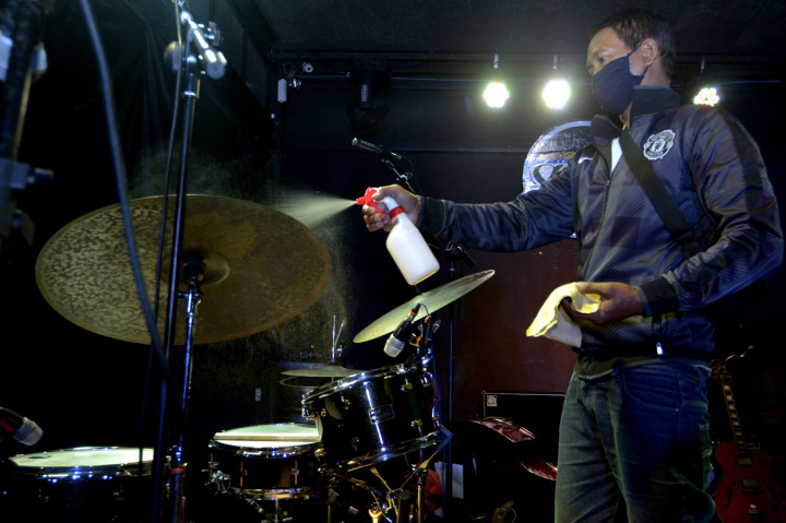 Seorang kru menyemprotkan cairan disinfektan ke alat musik yang akan digunakan musisi saat konser bertajuk 'Jazztreaming!' di Denpasar, Bali.