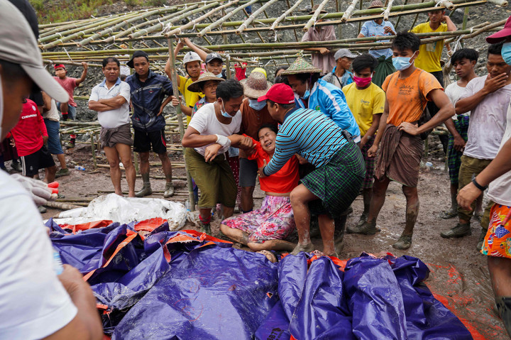 Tubuh penambang yang berlumuran lumpur dan berlumuran darah diletakkan di tanah dengan dibungkus terpal, sementara beberapa sepatu hilang karena kekuatan terjangan lumpur yang menimpa mereka. 
