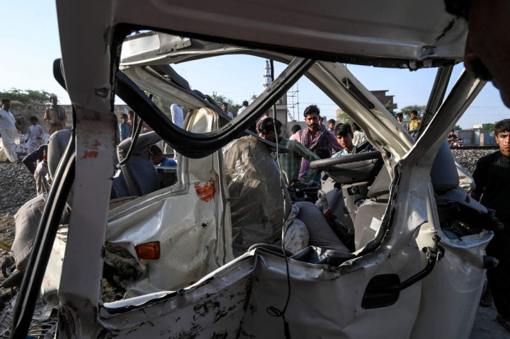 Warga berkerumun melihat bangkai mobil van yang hancur setelah ditabrak kereta api di wilayah Farooqabad, Distrik Sheikhupura, Provinsi Punjab, Pakistan, pada Jumat, 3 Juli 2020. 