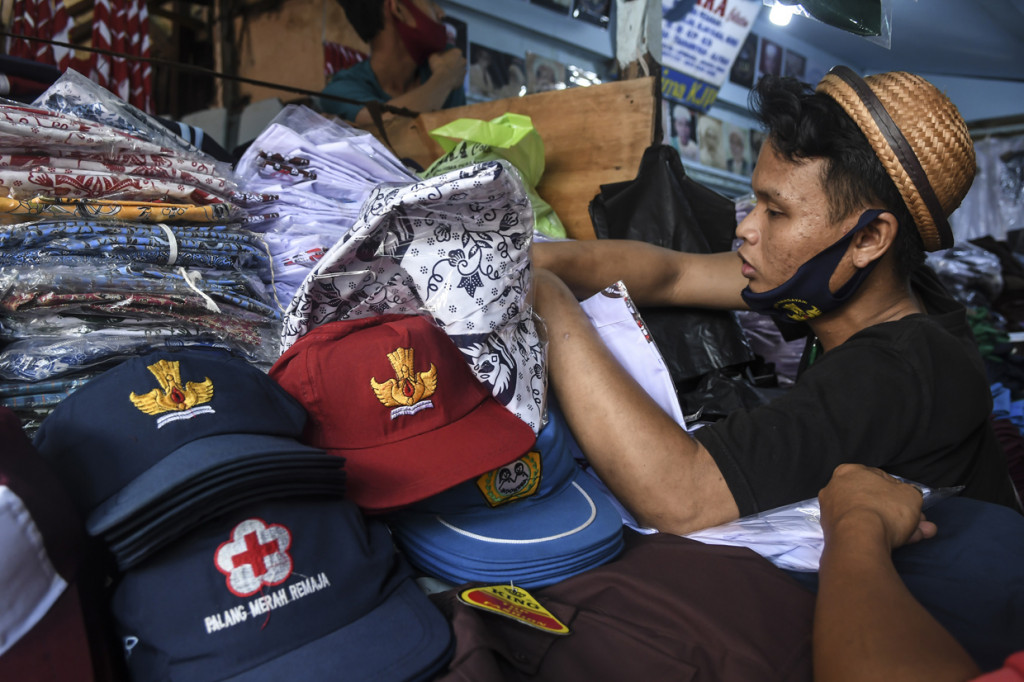 Pedagang seragam sekolah melayani pembeli di Pasar Jatinegara, Jakarta.
