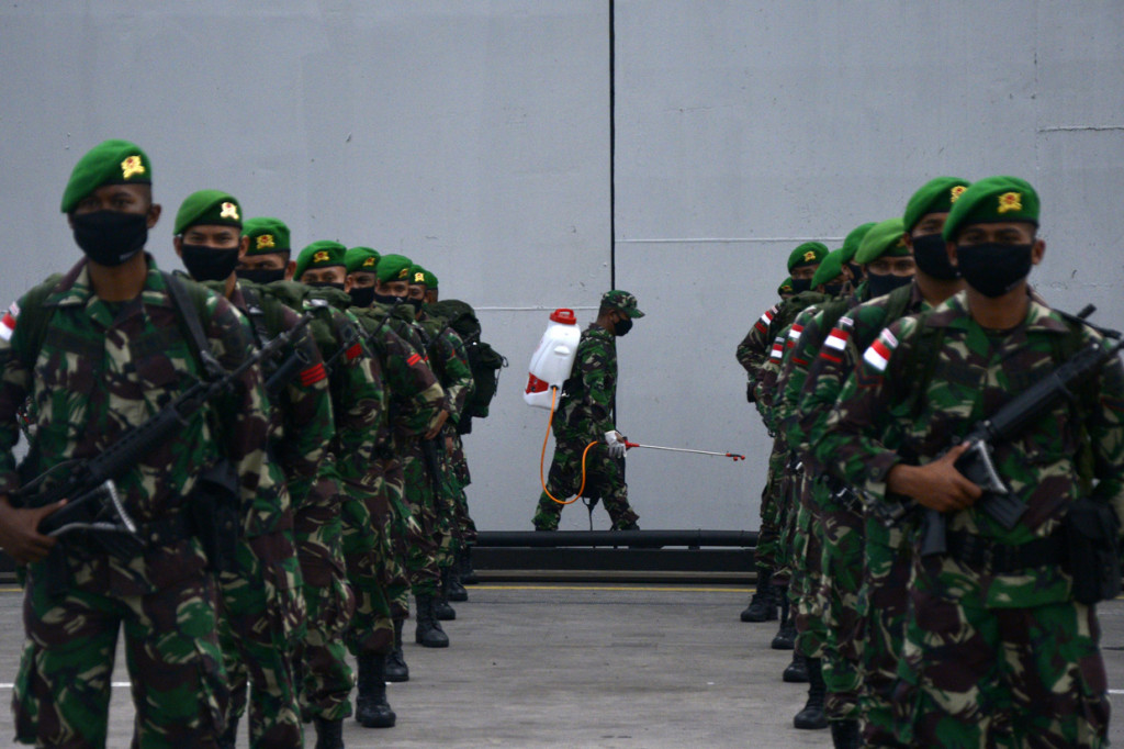 Seorang prajurit TNI AD menyemprotkan cairan disinfektan saat persiapan apel penyambutan kepulangan Satgas pengamanan perbatasan RI-Papua Nugini di Pelabuhan Sukarno Hatta, Makassar, Sulawesi Selatan.