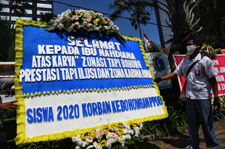 Relawan PPDB DKI Jakarta 2020 mengenakan seragam SMA berdiri di depan karangan bunga yang terpajang di Balai Kota, Jakarta.