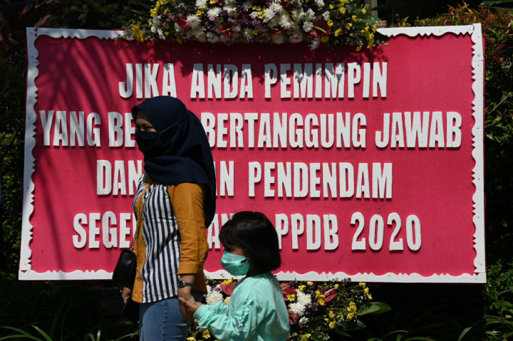 Warga melintas di depan karangan bunga yang terpajang di depan pintu masuk Balai Kota Jakarta, Jalan Medan Merdeka Selatan, Jakarta Pusat.