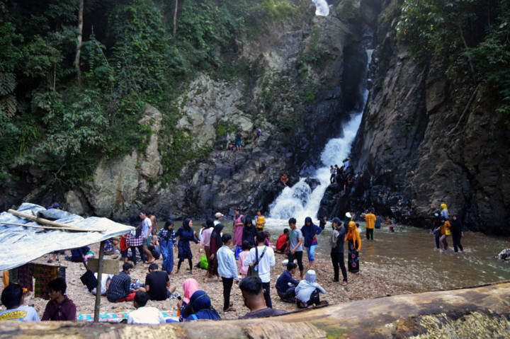 Wisatawan menikmati sejuknya curahan air dari air terjun (Curug) Dengdeng di Desa Leuwibatu, Kecamatan Rumpin, Kabupaten Bogor, Jawa Barat.