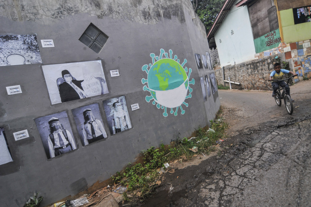 Pengendara sepeda melintasi foto yang dipamerkan di ruang publik daerah Jati Asih, Bekasi, Jawa Barat, Rabu.