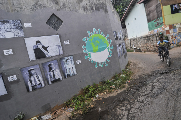 Pengendara sepeda melintasi foto yang dipamerkan di ruang publik daerah Jati Asih, Bekasi, Jawa Barat, Rabu.