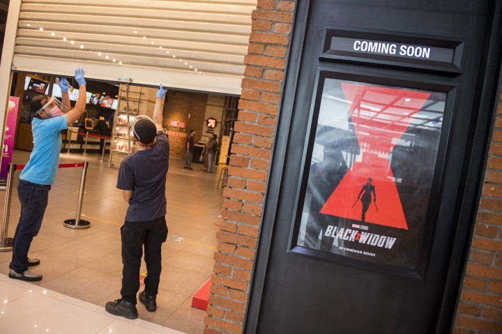 Pekerja menggunakan alat pelindung wajah saat menutup pintu seusai simulasi pembukaan dan peninjauan tempat hiburan bioskop CGV Cinemas di Bandung Electronic Center (BEC), Bandung, Jawa Barat.