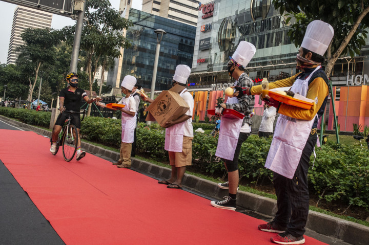 Anggota komunitas Bike to Work (B2W) Indonesia membagikan makanan dan minuman dalam aksi simpatik bertajuk Yang Bersepeda Yang Istimewa di Jalan Jenderal Sudirman, Senayan, Jakarta.