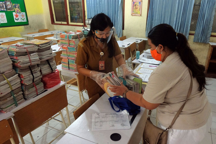 Sekolah di Denpasar masih belum melakukan belajar mengajar dengan tatap muka di sekolah pada hari pertama tahun ajaran baru. Kegiatan hanya diisi dengan pembagian rapor, hasil ulangan, pengembalian buku sebelumnya dan pengambilan buku baru oleh orang tua siswa dengan pembatasan pelayanan 30 menit tiap 10 orang untuk mencegah penularan covid-19. ANTARA FOTO/Nyoman Hendra Wibowo