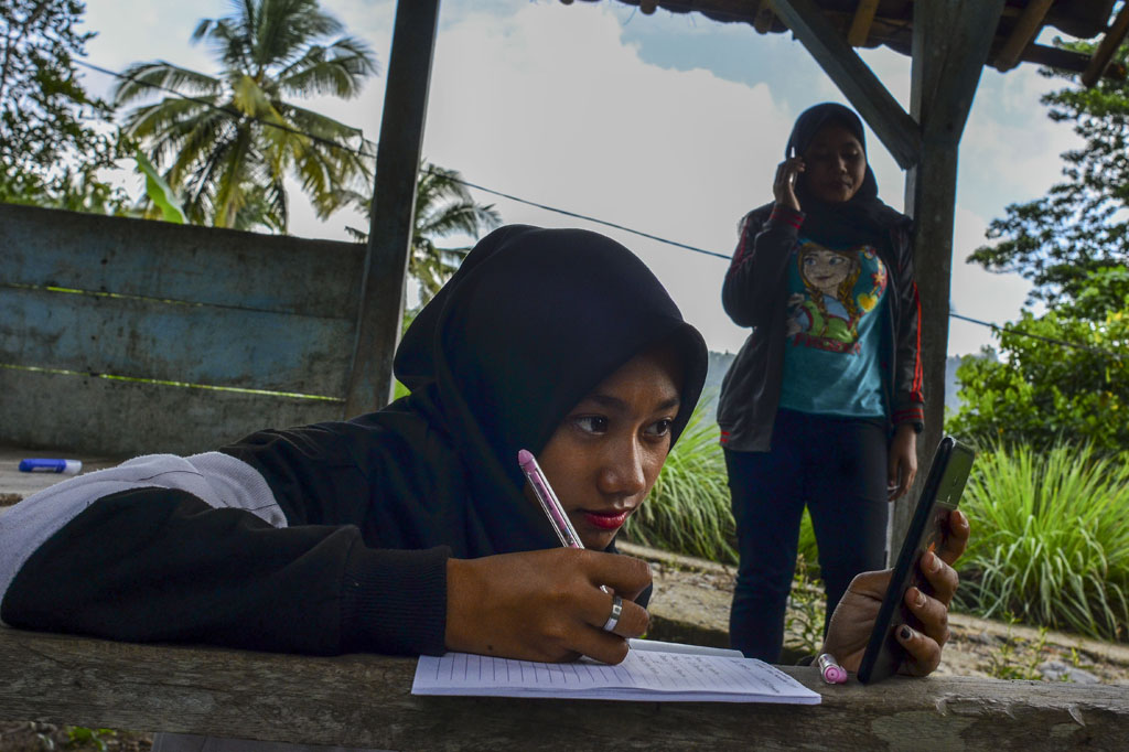 Siswa kelas IX Sekolah Menengah Pertama (SMP) Plus Pasawahan mengerjakan tugas sekolah di pos kamling Desa Pasawahan, Kabupaten Ciamis, Jawa Barat, Kamis, 16 Juli 2020.
